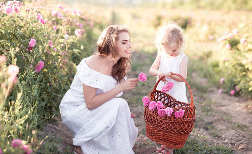 Happy mother and daughter picking flowers on field