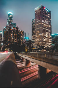 Illuminated modern buildings in city against sky at night