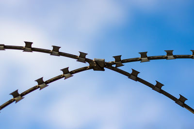 Razor wire fences against the cloudy sky
