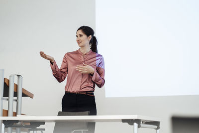 Confident businesswoman giving presentation during meeting in office