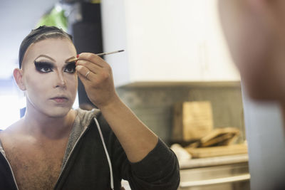 Young man applying drag makeup