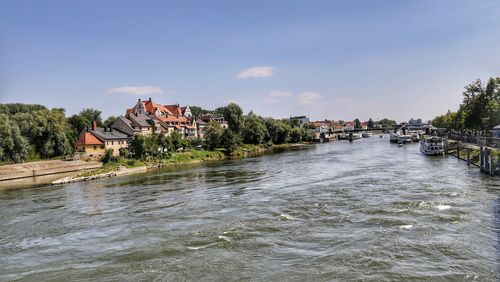 Scenic view of river by buildings against sky