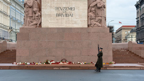 Rear view of man and woman standing by statue in city