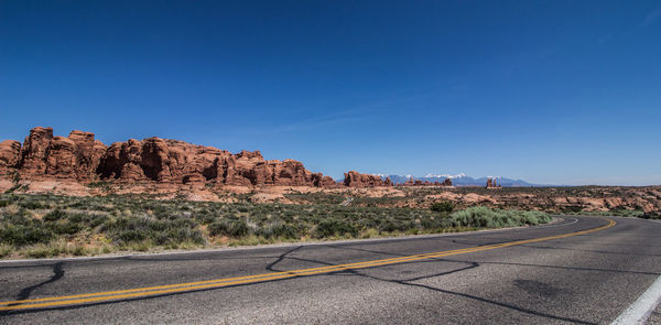 Road by rock formations against blue sky