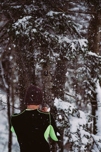 Rear view of man exercising by tree on field during winter