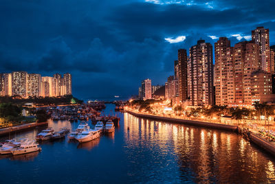 Canal by illuminated buildings against sky at night