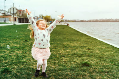 Full length of smiling girl standing on grass