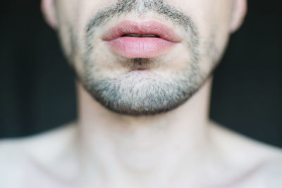 Midsection of shirtless man against black background