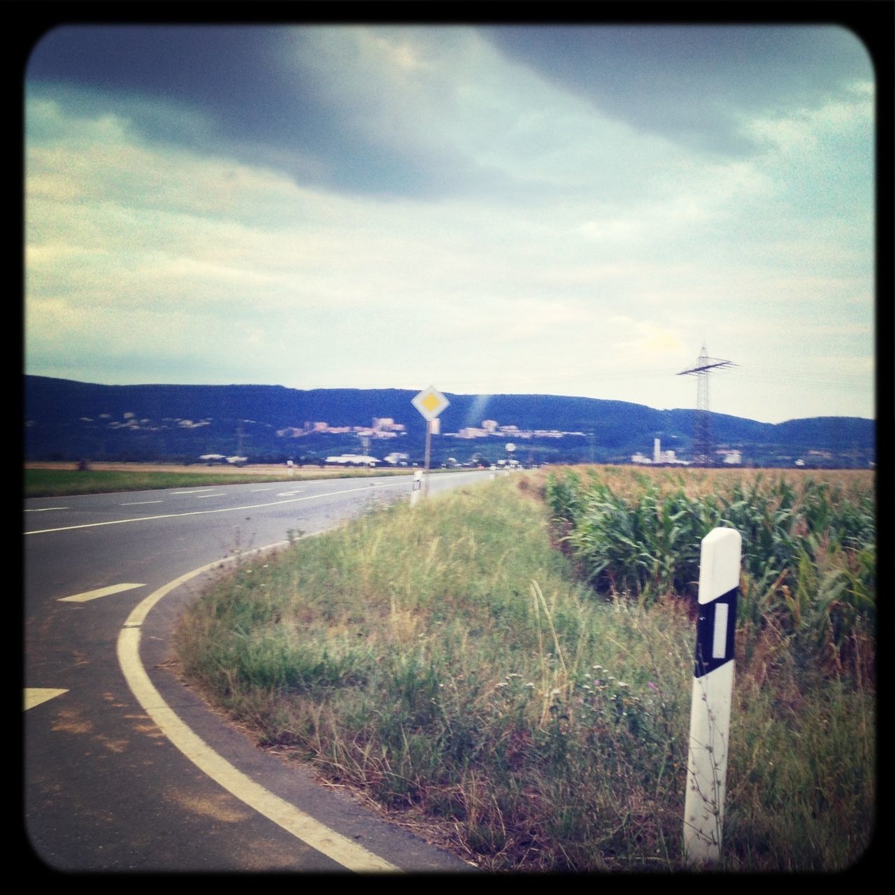 transfer print, sky, auto post production filter, road, grass, transportation, landscape, cloud - sky, field, cloud, road marking, the way forward, country road, day, grassy, no people, nature, outdoors, tranquility, road sign