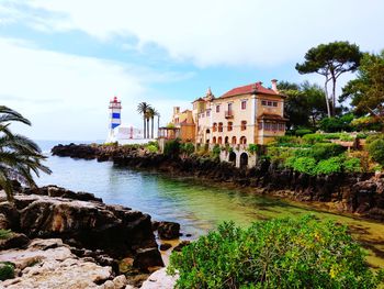 Buildings by sea against sky