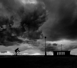 Low angle view of silhouette man on bicycle against sky