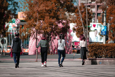 Rear view of people walking on street in city