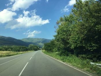 Road amidst trees against sky