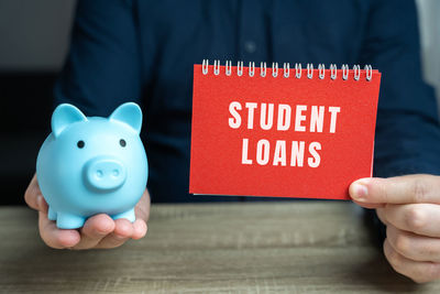 Midsection of man holding piggy bank on table