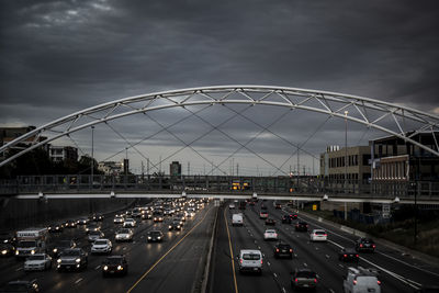 Cars moving on road against cloudy sky