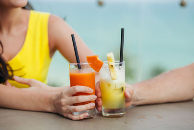 Midsection of people holding drinks on table