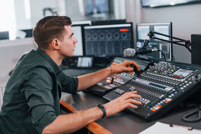 Young man is indoors in the radio studio is busy by broadcast.