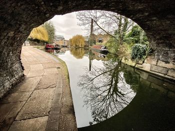 Reflection of trees on bridge against river