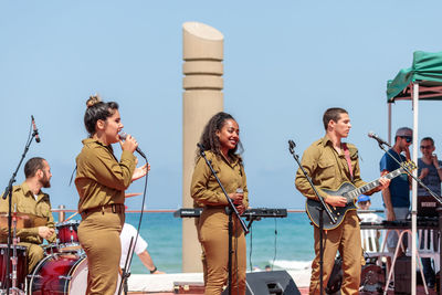 People standing by sea against clear sky