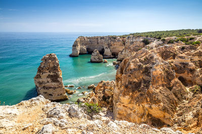 Scenic view of rocks in sea against blue sky