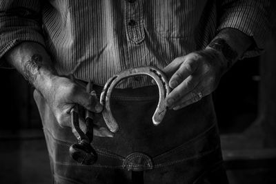 Midsection of man holding horseshoe