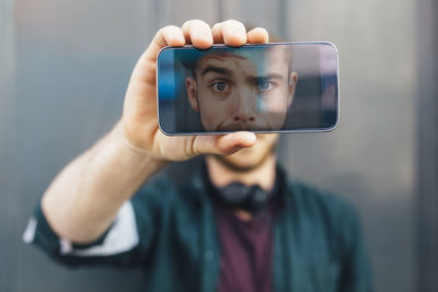 Display of smartphone showing young man pulling funny face