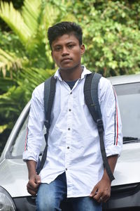 Portrait of young man standing on car
