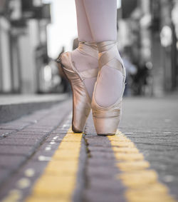 Low section of female ballet dancer dancing on road