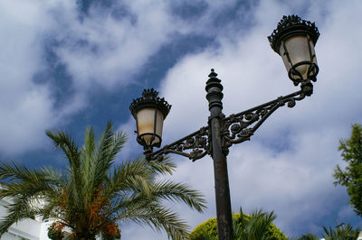 Low angle view of street light and palm trees against sky