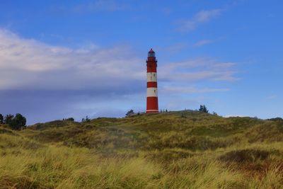 Lighthouse on field against sky