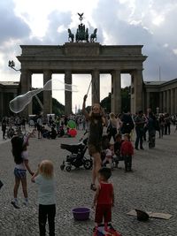 People at town square against cloudy sky