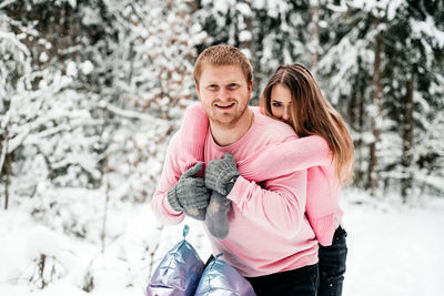 Portrait of happy woman with snow against trees during winter