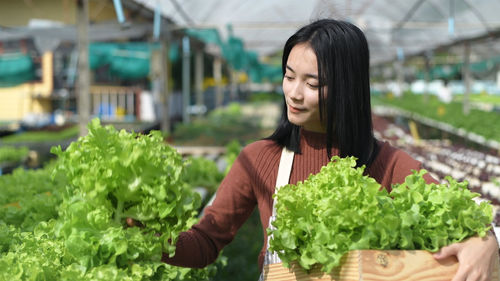 Woman looking away while standing in greenhouse