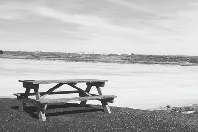 Empty bench on shore of a frozen lake