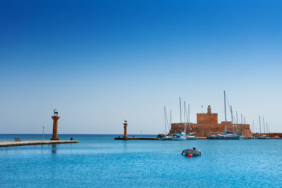 Sailboats in sea against clear blue sky