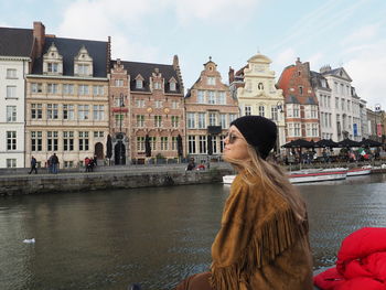 People on canal against buildings in city