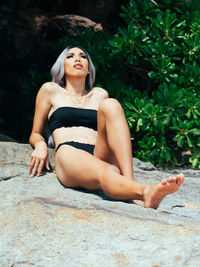 Portrait of young trans woman sitting on rock