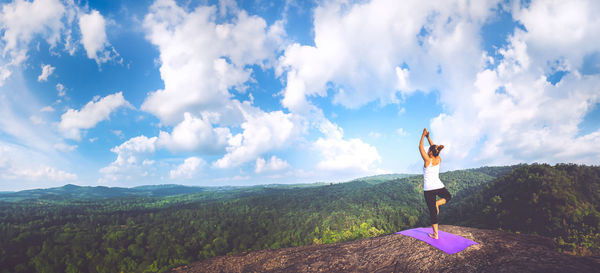 Rear view of man standing on mountain against sky