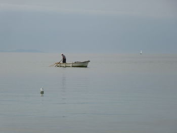 People on boat in sea against sky