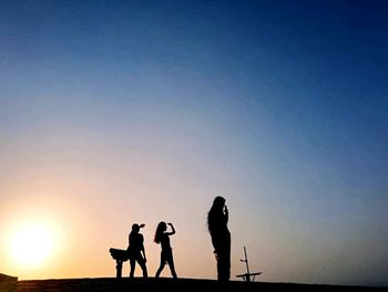 Silhouette people standing against sky during sunset