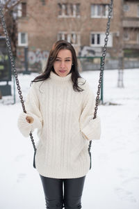 Young woman swinging in snow covered playground