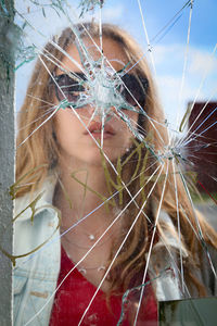 Reflection of young woman on broken mirror