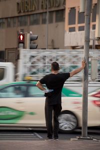 Full length of man standing on car in city