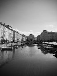 Boats moored in canal by buildings against sky in city