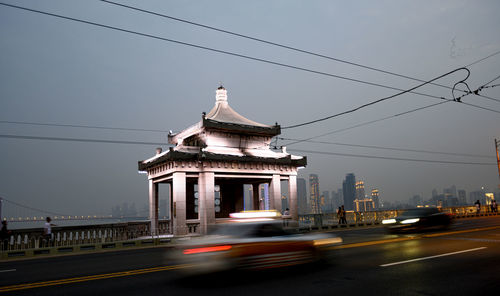 Cars on road by building against sky in city