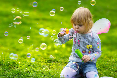 Full length of cute girl playing with bubbles