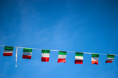 Low angle view flag bunting against blue sky