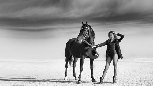 Beautiful woman standing by horse at desert