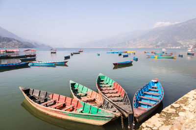 Boats moored on sea against mountains