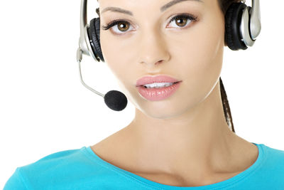 Close-up of young woman wearing headphones against white background